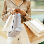 Woman holding shopping bags and using phone