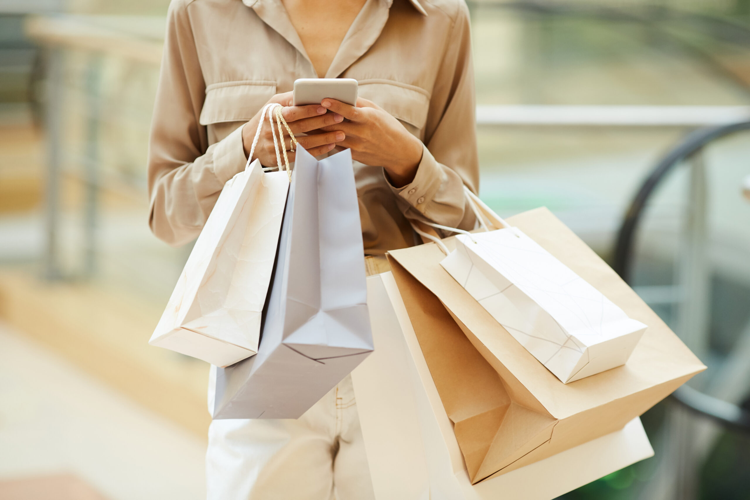 Woman holding shopping bags and using phone