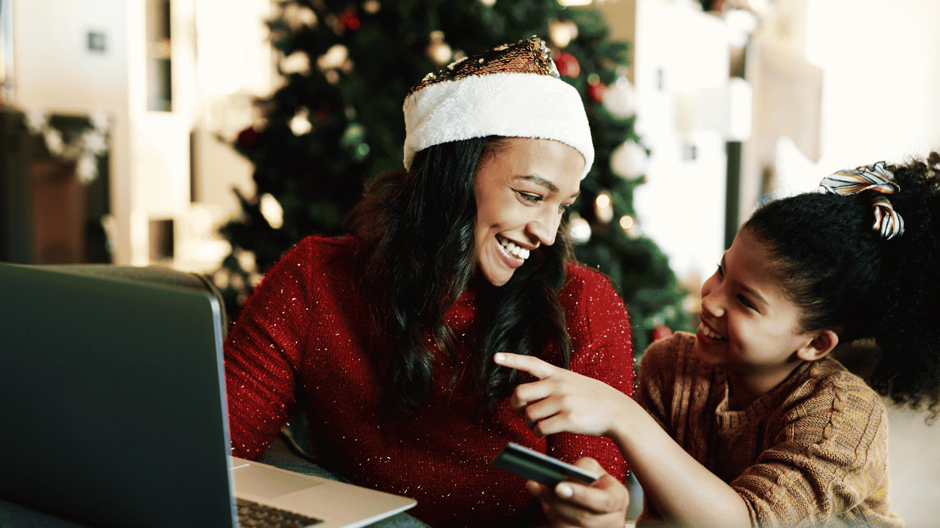 Woman and daughter online shopping wearing Santa hat