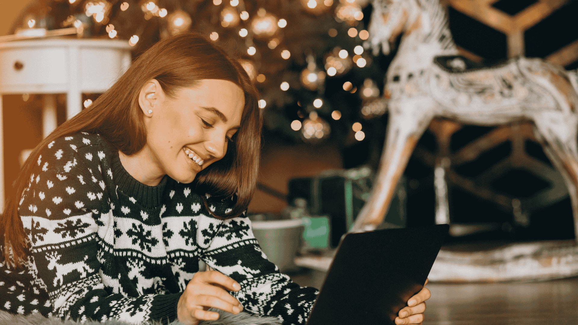 Woman in holiday sweater online shopping